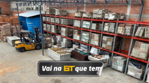 Telhas, tijolos, pedras, caixa d'água, madeira, ferro, pisos, azulejos, material de construção, nichos, material organizado em um galpão. Estoque da madeireira.