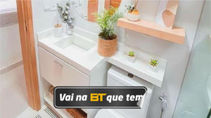 Banheiro compacto com o espaço otimizado através da disposição inteligente dos elementos, aproveitamento dos espaços verticais e integração dos móveis, além do uso de cores clara e prateleiras.